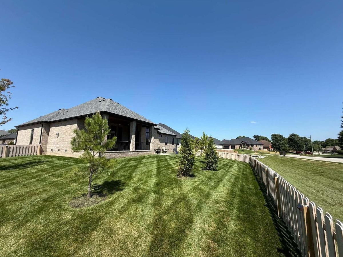 Brick home with a striped lawn along a wood fence