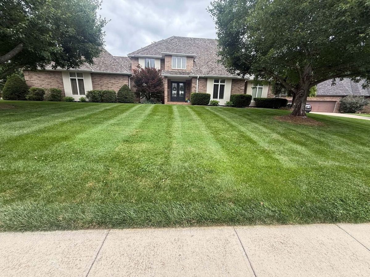 Large brick home with a striped front lawn