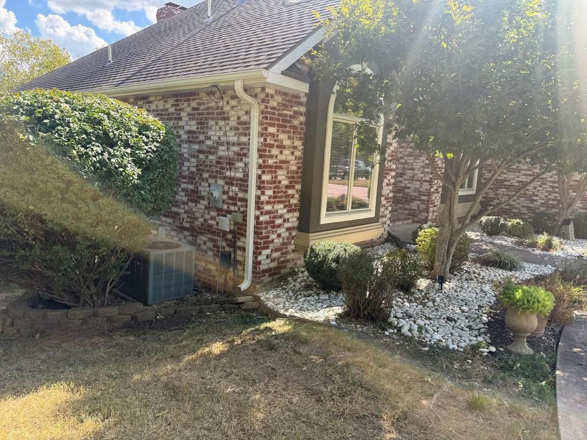 Decorative rock bed and shrubs along a brick home