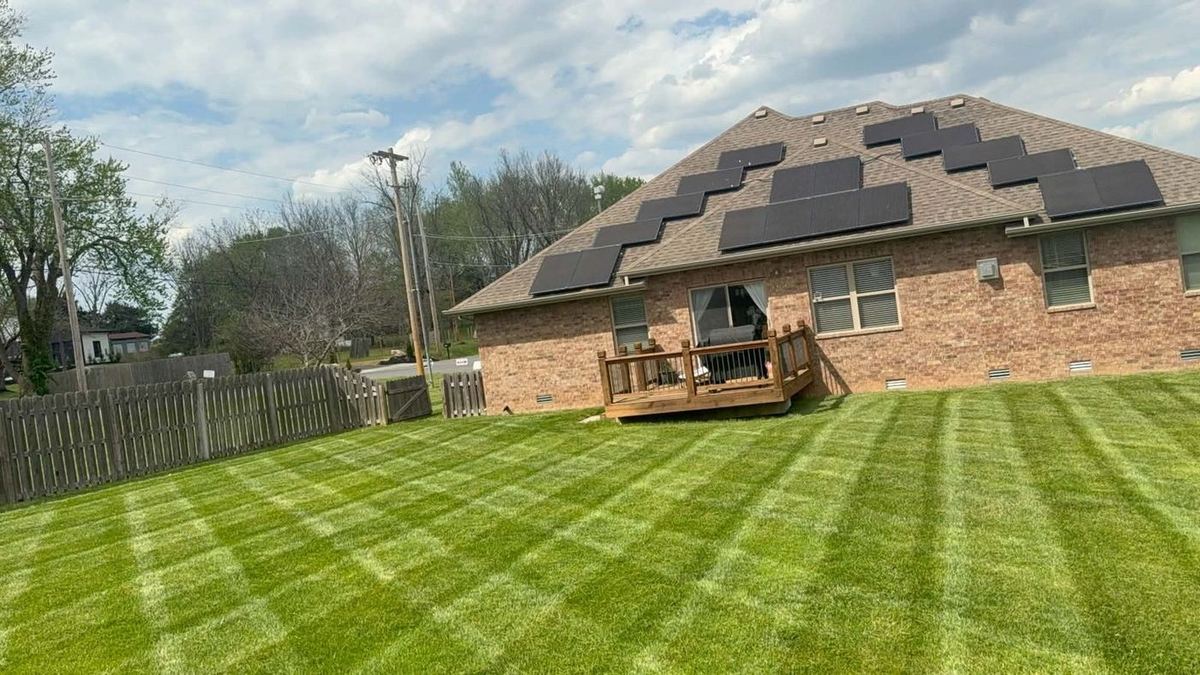 Striped backyard behind a brick home with solar panels