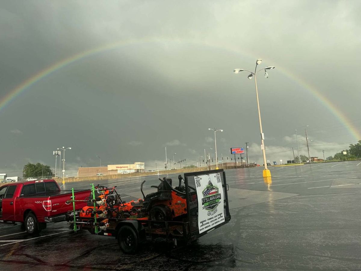 Truck and mower trailer under a rainbow after a storm
